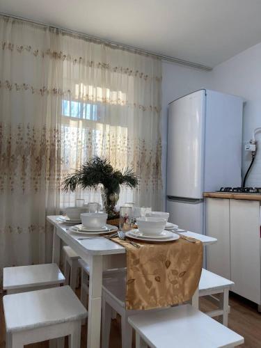 uma cozinha com uma mesa com cadeiras e um frigorífico em Дизайнерская трехкомнатная квартира em Karaganda