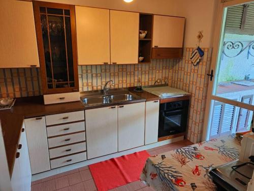 una cocina con armarios blancos y fregadero en Ridente villetta a schiera, 10min a piedi dal mare, en San Felice Circeo