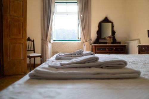 a pile of towels sitting on top of a bed at Casa Mindela Farmhouse in Vila do Conde
