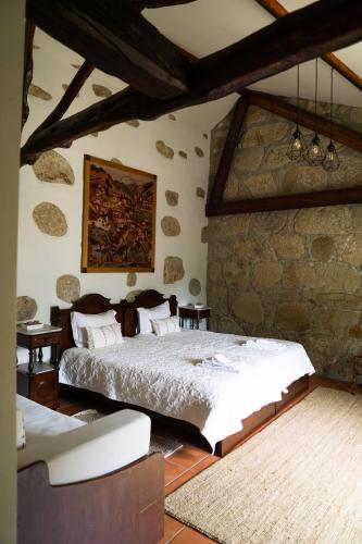 a bedroom with a bed and a stone wall at Casa Mindela Farmhouse in Vila do Conde