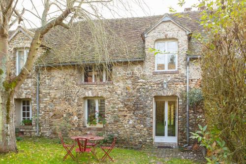 a stone house with a table in front of it at Le Moulin de Dannemarie in Dannemarie