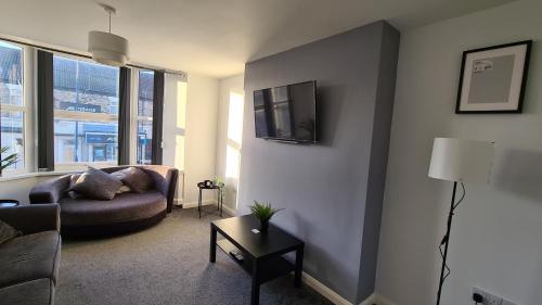 a living room with a couch and a tv on a wall at The "Cleveland" Apartment in Redcar