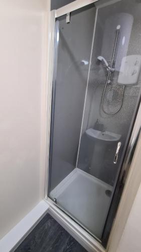 a glass shower door with a sink in a bathroom at The "Cleveland" Apartment in Redcar
