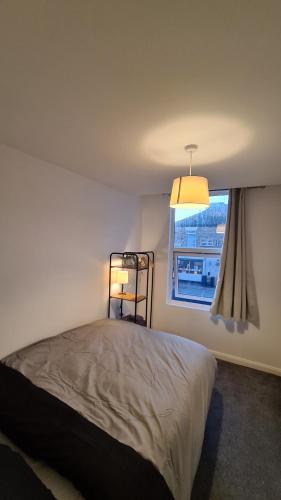 a bedroom with a bed with a lamp and a window at The "Cleveland" Apartment in Redcar