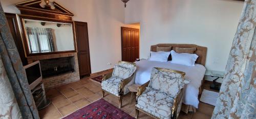 a bedroom with a bed with two chairs and a fireplace at Faqra Palace in Kfardebian