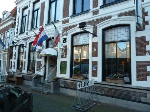 a building with flags and a sign in front of it at Hotel Centraal in Harlingen