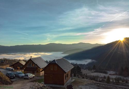 una vista de un pueblo con el sol saliendo sobre las montañas en Tarovuk cabin, en Zaovine