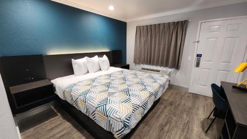 a hotel room with a bed with a blue wall at Studio 6 Suites San Ysidro CA San Diego South Bay in San Ysidro, San Diego