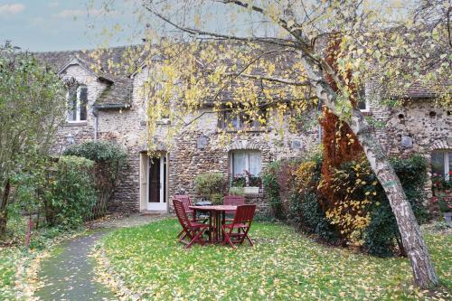 a table and chairs in front of a stone house at Le Moulin de Dannemarie in Dannemarie