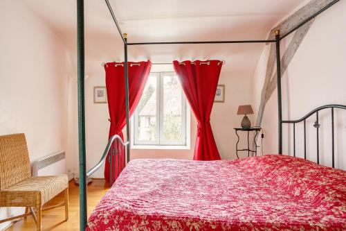 a bedroom with a canopy bed and red curtains at Le Moulin de Dannemarie in Dannemarie