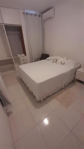 Cama blanca en habitación con suelo de baldosa en Apartamento Bonavides, en Fortaleza