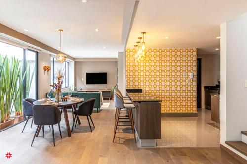 a dining room and living room with a yellow wall at Casa Anatole France by Kukun in Mexico City