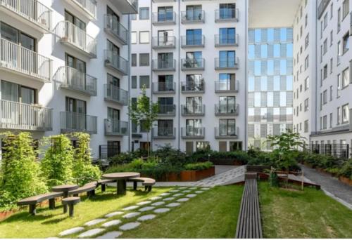 un patio con bancos y mesas frente a un edificio en Solna Property Apartment, en Estocolmo