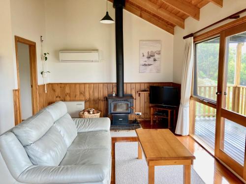 a living room with a white couch and a wood stove at Daysy Hill Country Cottages in Port Campbell