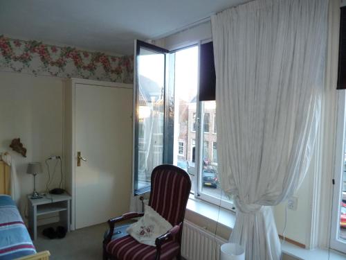 a bedroom with a chair and a large window at Hotel Centraal in Harlingen