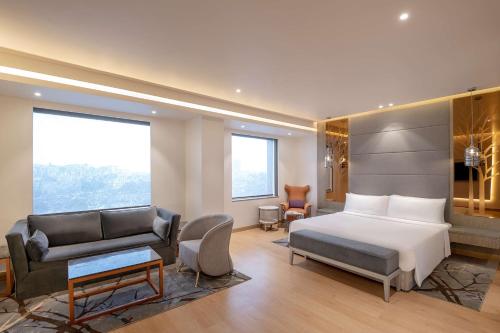 ガーズィヤーバードにあるRadisson Blu Towers Kaushambi Delhi NCRのベッドとソファ付きのホテルルーム
