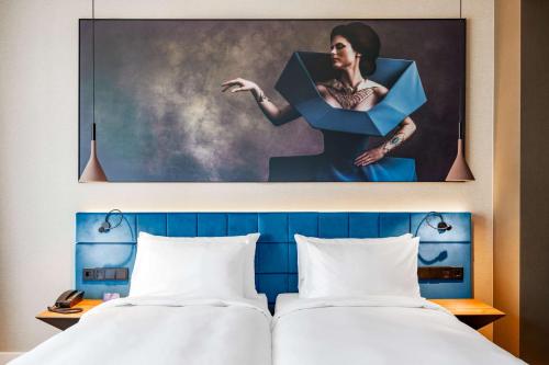 two beds in a hotel room with a painting on the wall at Radisson Blu Aurum Hotel, Brasov in Braşov