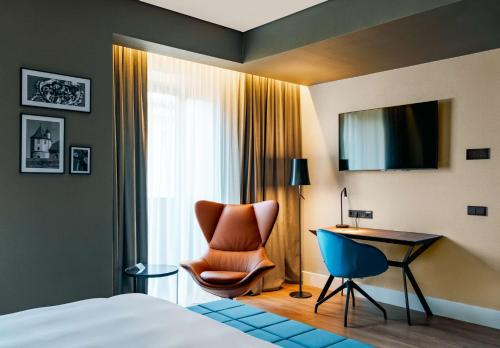 a hotel room with a bed and a chair and a desk at Radisson Blu Aurum Hotel, Brasov in Braşov