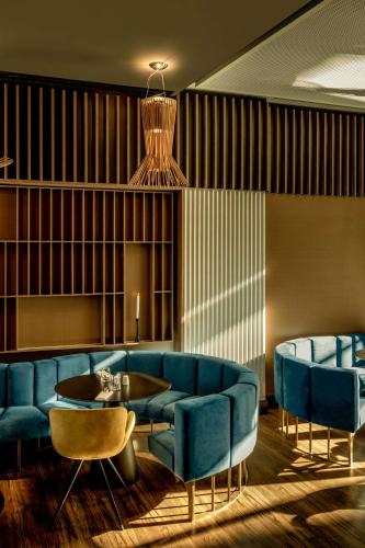 a living room with a blue couch and a table and chairs at Radisson Blu Aurum Hotel, Brasov in Braşov