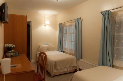 a bedroom with two beds and a desk and a window at Oak Inn in Upton Snodsbury