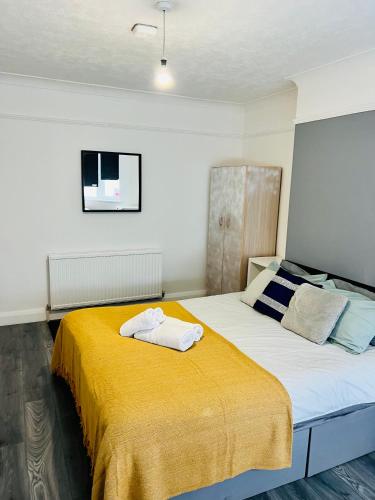 a bedroom with a large bed with a yellow blanket at Beautiful Private Rooms in London Central Willesden Green in London