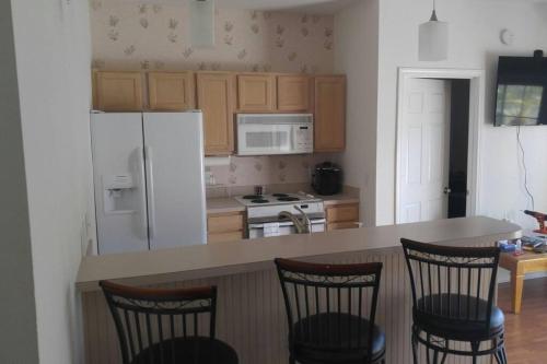 a kitchen with a white refrigerator and a counter with chairs at Two bedroom Sea Trail condo in Sunset Beach in Sunset Beach
