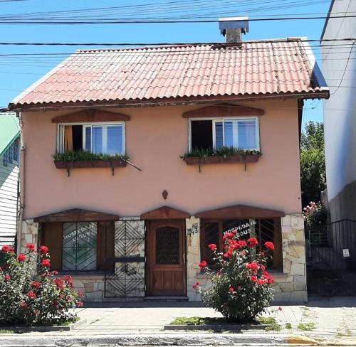 une petite maison avec deux fenêtres et des fleurs rouges dans l'établissement Hospedaje Legus, à San Carlos de Bariloche
