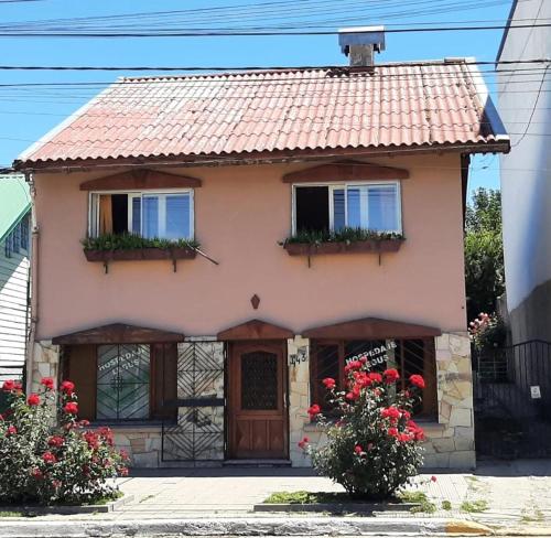 Casa pequeña con 2 ventanas y flores rojas en Hospedaje Legus en San Carlos de Bariloche