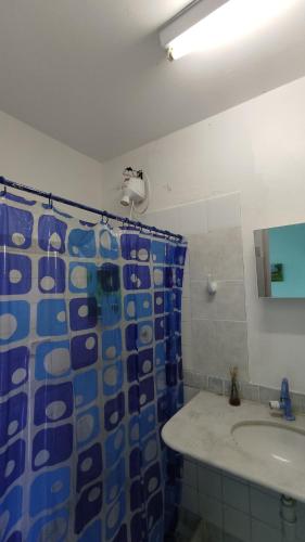 a bathroom with a blue shower curtain and a sink at Refúgio da Mangueira in Barra dos Coqueiros
