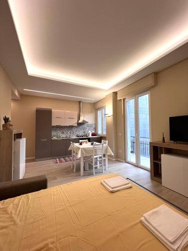 a living room with a large bed and a kitchen at CASA DANTE: Oneglia Centro-Marina-Spiagge (3 min) in Imperia