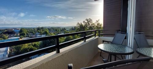 balcón con vistas y 2 mesas y sillas en Ainil Apartment, en Valdivia