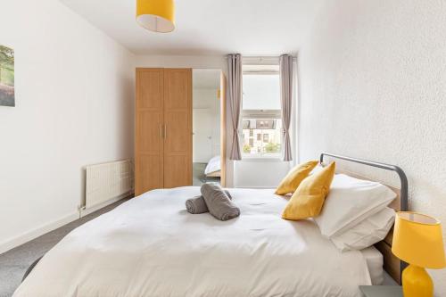 a bedroom with a large white bed with yellow pillows at Spacious stylish centraly located flat near beach in Largs