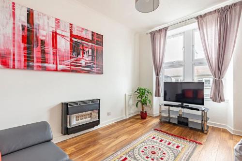 a living room with a couch and a tv at Spacious stylish centraly located flat near beach in Largs