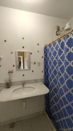 a bathroom with a sink and a blue shower curtain at A Pousada. in Barra dos Coqueiros