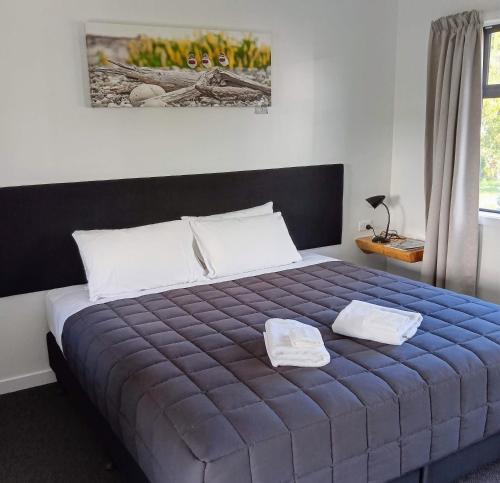 a bedroom with a blue bed with two pillows at Last Light Lodge in Tuatapere