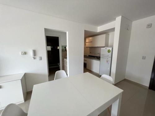 cocina blanca con mesa blanca y sillas en Torre Leonardo I en Villa Carlos Paz