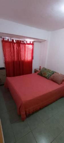1 dormitorio con cama roja y cortina roja en Depto centro en Villa Gesell
