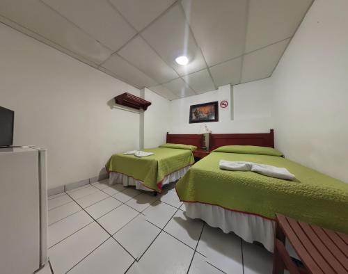 2 Betten in einem Zimmer mit grüner Bettwäsche in der Unterkunft Hotel San Jose de la Montaña in San Salvador