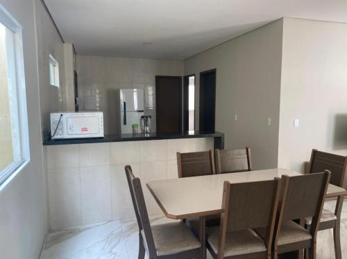 a dining room with a table and chairs and a microwave at Bela Casa com 3 quartos mobiliada na Zona Leste in Teresina