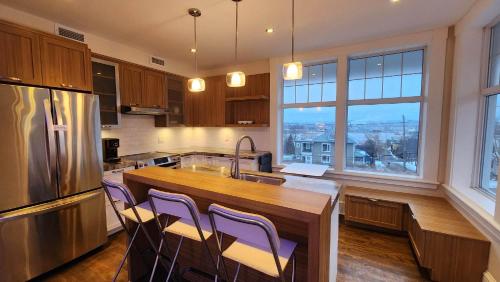 a kitchen with a kitchen island with purple chairs at Les Suites KAISHI in Lévis