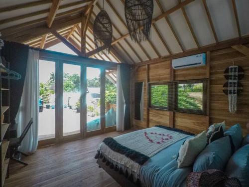 a bedroom with a large bed in a room with windows at Rumah Tara Modern 3 bedroom pool and garden villa in Gili Air in Gili Islands