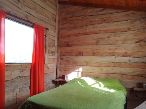 ein Schlafzimmer mit einer Holzwand mit einem Bett und einem Fenster in der Unterkunft Casa Ecológica Rama & Cabaña Rústica in Tandil