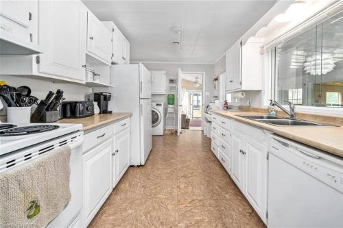 a white kitchen with white cabinets and appliances at Pines Bay Waterfront cottage with Hot tub! in Kawartha Lakes