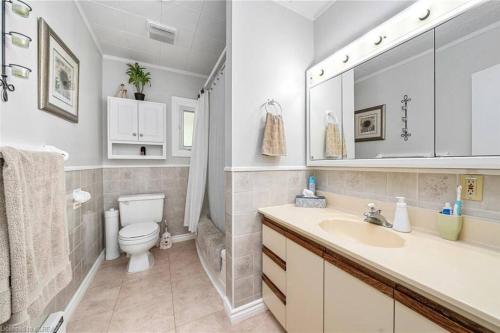 a bathroom with a sink and a toilet and a mirror at Pines Bay Waterfront cottage with Hot tub! in Kawartha Lakes