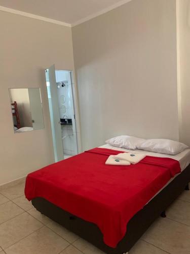 a bedroom with a bed with a red blanket and a mirror at Hotel Central de Anápolis in Anápolis