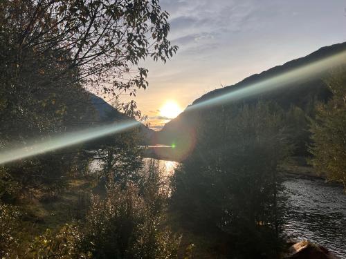 um pôr-do-sol sobre um rio com o sol a brilhar em Refugio Macales em Puerto Dunn