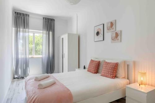 biała sypialnia z dużym łóżkiem i oknem w obiekcie Lovely 3-bedroom condo w/ free parking on premises w mieście Queluz