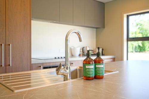 two bottles of wine sitting next to a kitchen sink at Parehua Resort in Martinborough 