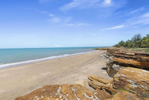 a sandy beach with rocks and the ocean at 'Botanica Fresca' Chic Nightcliff Convenience in Darwin