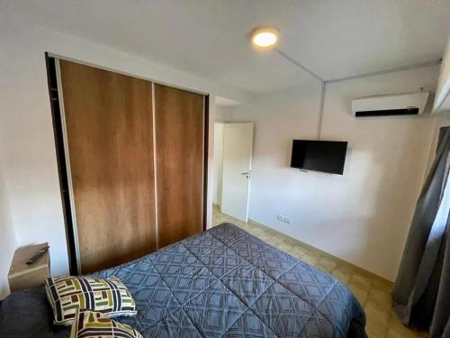 1 dormitorio con 1 cama y TV en la pared en San Juan Primero en San Bernardo